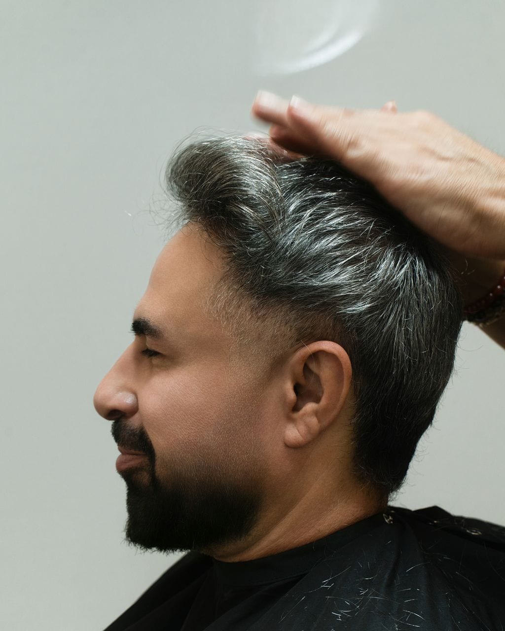 Client in profile with his hair set, Moses's hand still at the crown