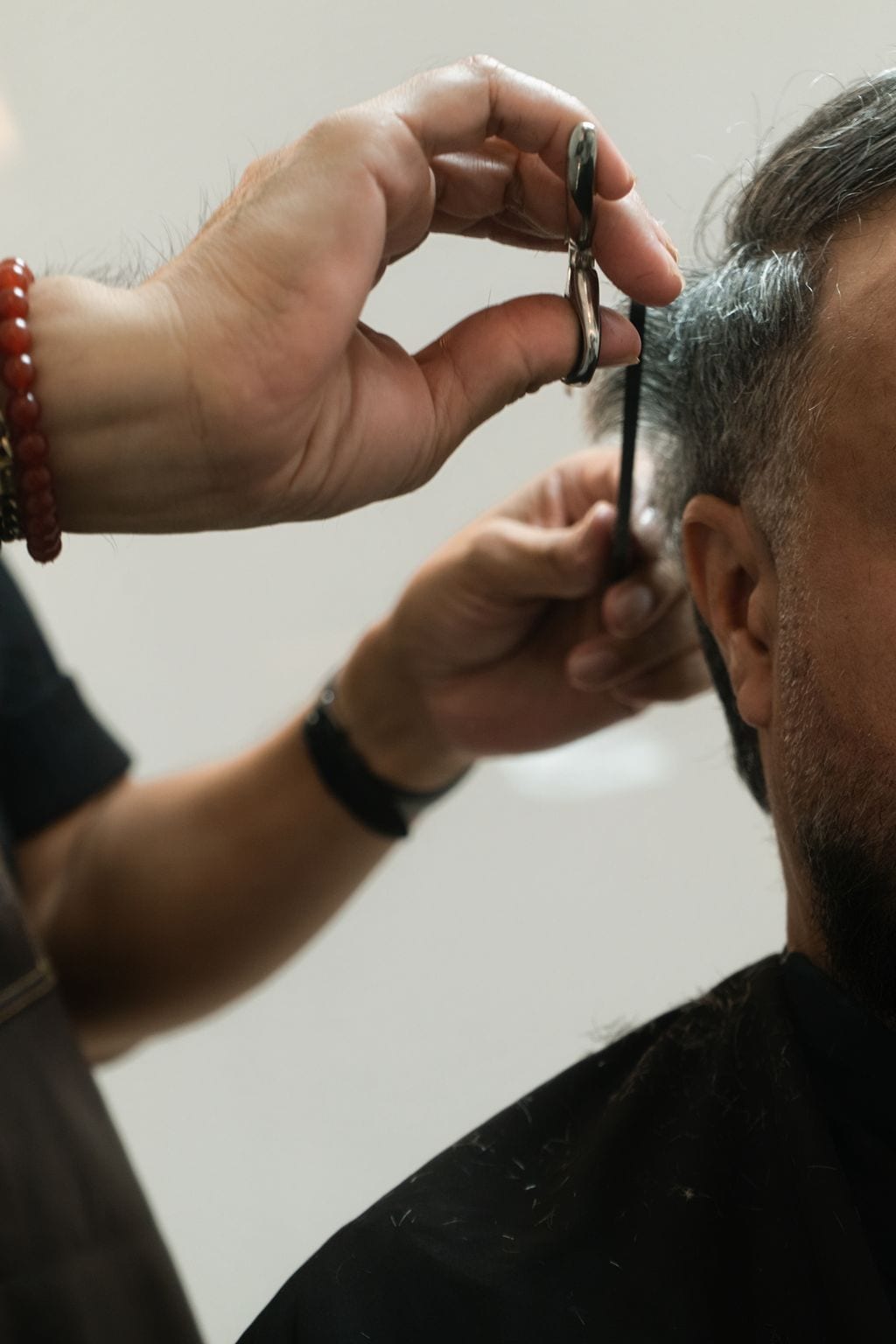 Moses's hand lifting scissors and comb beside a client's ear